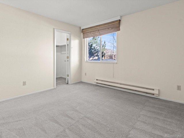 empty room featuring a baseboard heating unit, light carpet, and baseboards