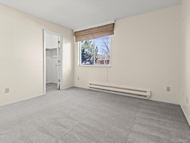 spare room featuring a baseboard radiator, baseboards, and carpet