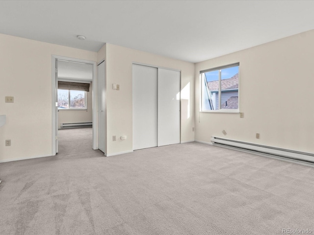 unfurnished bedroom with multiple windows, baseboard heating, and light colored carpet