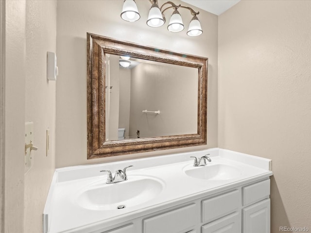 full bathroom featuring toilet, double vanity, and a sink