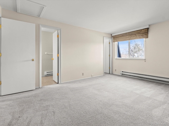 spare room featuring a baseboard radiator, attic access, and light colored carpet