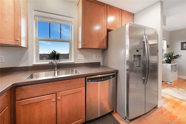 1544 Cottonwood Ave, Lafayette, CO 80026 - kitchen with brown cabinetry, a sink, appliances with stainless steel finishes, dark countertops, and light wood-type flooring