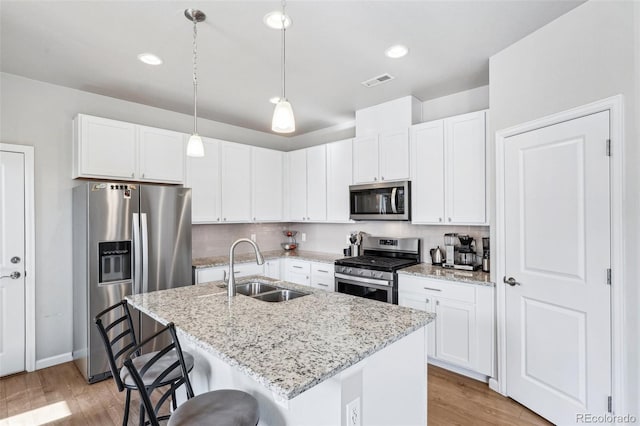 19733 W 93rd Ln Unit A, Arvada, CO 80007 - kitchen featuring appliances with stainless steel finishes, a sink, light wood-style floors, tasteful backsplash, and a breakfast bar area