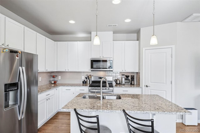 19733 W 93rd Ln Unit A, Arvada, CO 80007 - kitchen featuring appliances with stainless steel finishes, a sink, light wood-style floors, decorative backsplash, and white cabinetry