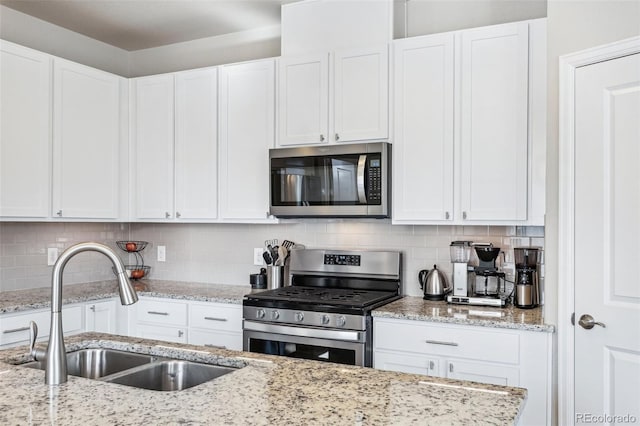 19733 W 93rd Ln Unit A, Arvada, CO 80007 - kitchen with appliances with stainless steel finishes, a sink, white cabinets, decorative backsplash, and light stone countertops