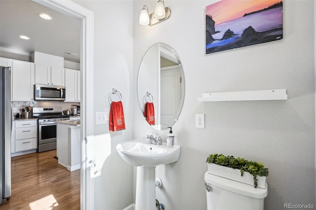 19733 W 93rd Ln Unit A, Arvada, CO 80007 - bathroom featuring toilet, wood finished floors, recessed lighting, decorative backsplash, and a sink