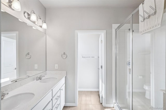 19733 W 93rd Ln Unit A, Arvada, CO 80007 - bathroom featuring double vanity, a shower stall, toilet, baseboards, and tile patterned floors