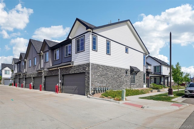 19733 W 93rd Ln Unit A, Arvada, CO 80007 - view of home's exterior featuring stone siding, an attached garage, a residential view, and driveway