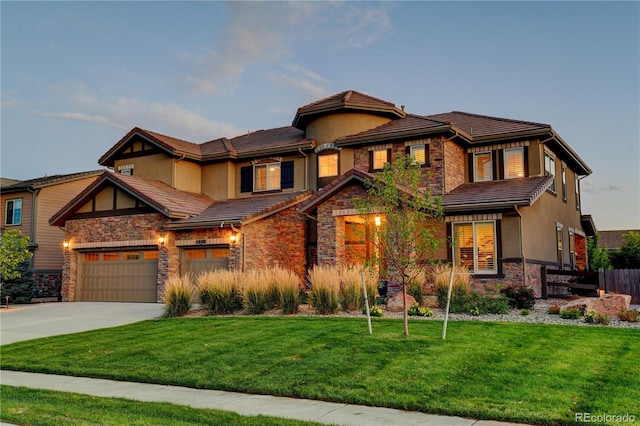 view of front of property with a front yard, stucco siding, concrete driveway, stone siding, and a tile roof