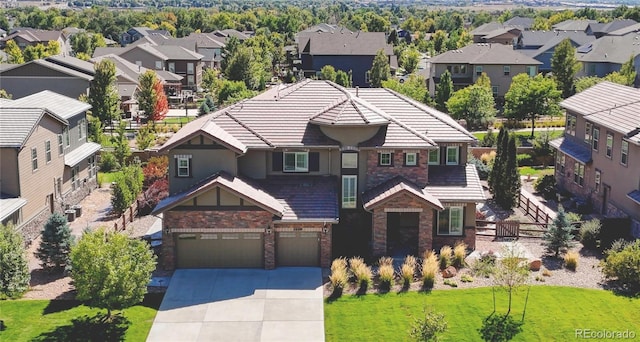 view of front of home with concrete driveway, a front lawn, a garage, stone siding, and a residential view