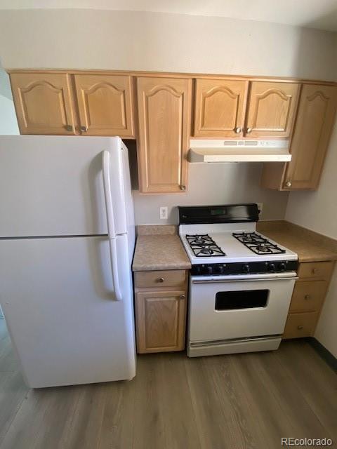 kitchen with light brown cabinets, white appliances, and dark hardwood / wood-style flooring