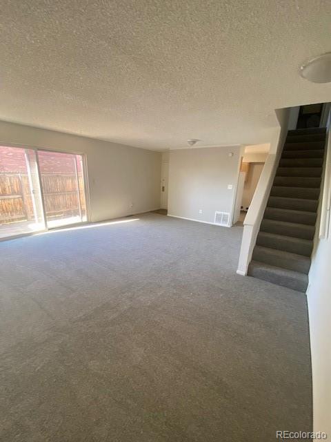 unfurnished living room with a textured ceiling and carpet floors