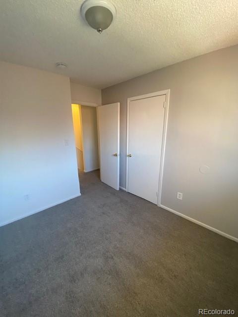 unfurnished bedroom with dark colored carpet and a textured ceiling