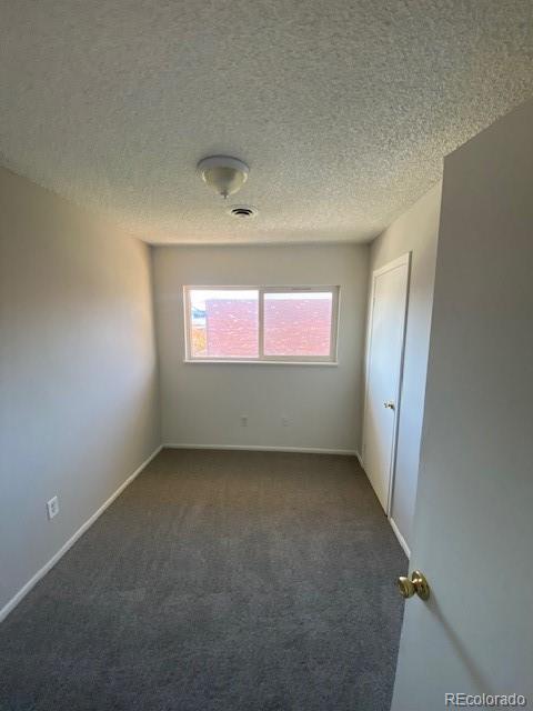 carpeted empty room featuring a textured ceiling