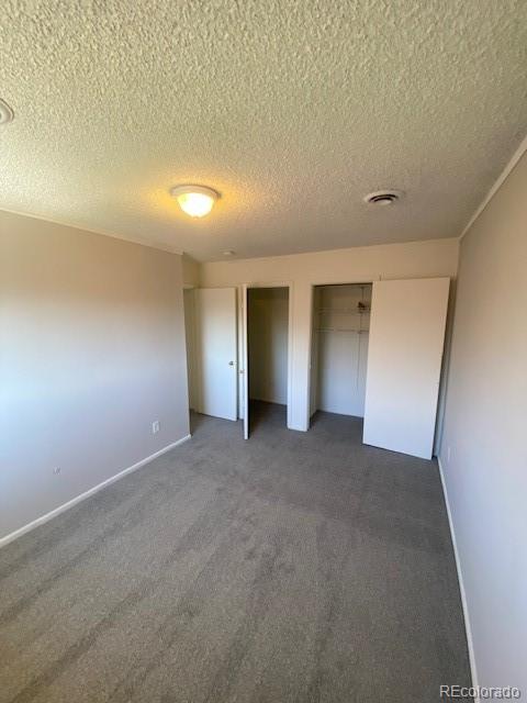 unfurnished bedroom featuring a textured ceiling and dark colored carpet