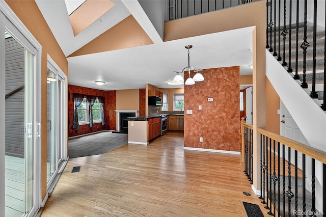 4386 W Deertrail Ct, Castle Rock, CO 80109 - kitchen with light wood-style flooring, dark countertops, open floor plan, black microwave, and high vaulted ceiling