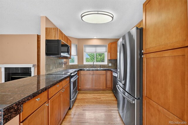 4386 W Deertrail Ct, Castle Rock, CO 80109 - kitchen featuring appliances with stainless steel finishes, tile countertops, light wood-type flooring, brown cabinets, and backsplash