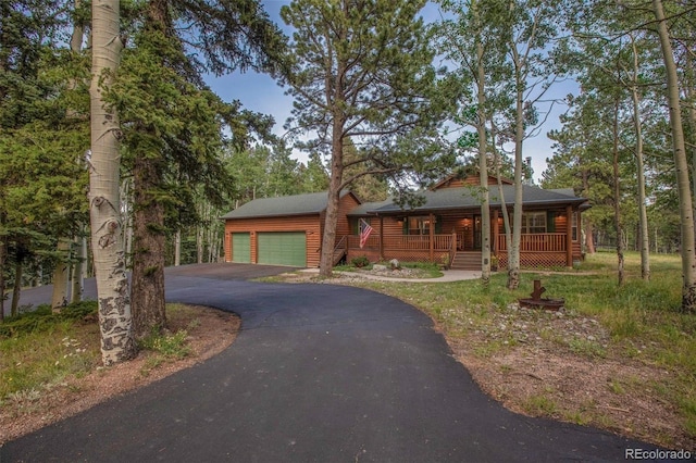 view of front of house featuring covered porch, driveway, an outdoor structure, and a garage