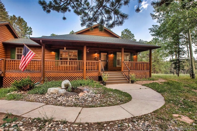 log-style house featuring covered porch and a shingled roof