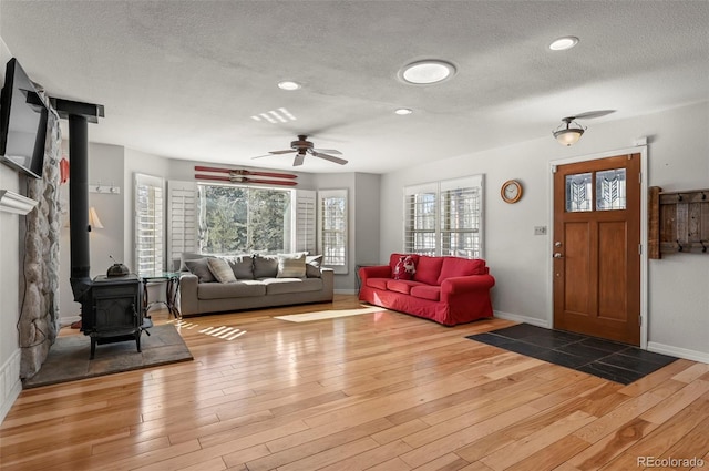 unfurnished living room with a textured ceiling, wood finished floors, and a wood stove