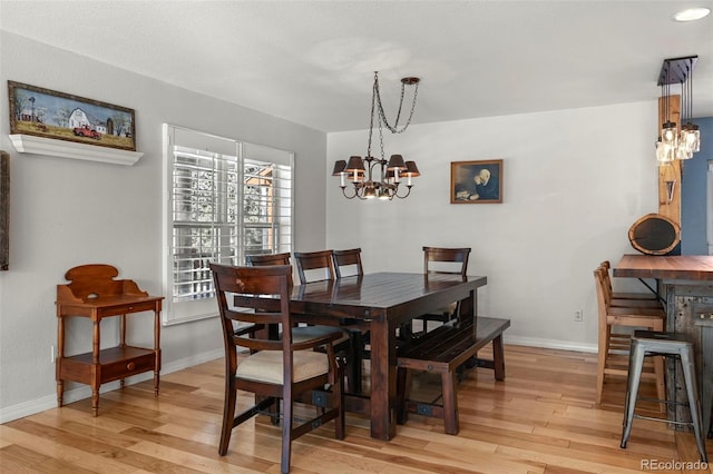 dining area featuring a notable chandelier, light wood finished floors, and baseboards