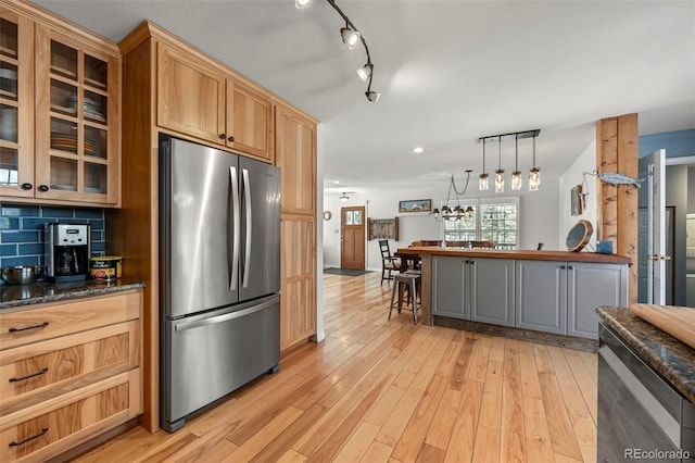 kitchen featuring glass insert cabinets, freestanding refrigerator, light wood-type flooring, a kitchen bar, and pendant lighting