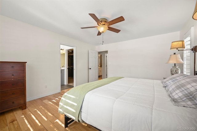 bedroom featuring a ceiling fan, a walk in closet, baseboards, and wood finished floors