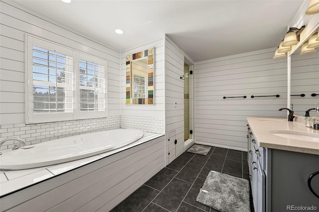 bathroom with wood walls, vanity, a bath, and tile patterned floors