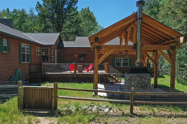 exterior space featuring a shingled roof, faux log siding, fence, and a wooden deck