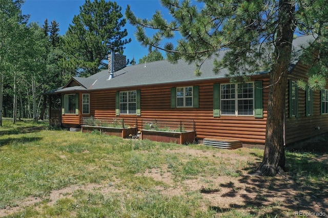 rear view of property featuring log veneer siding, a garden, and a chimney