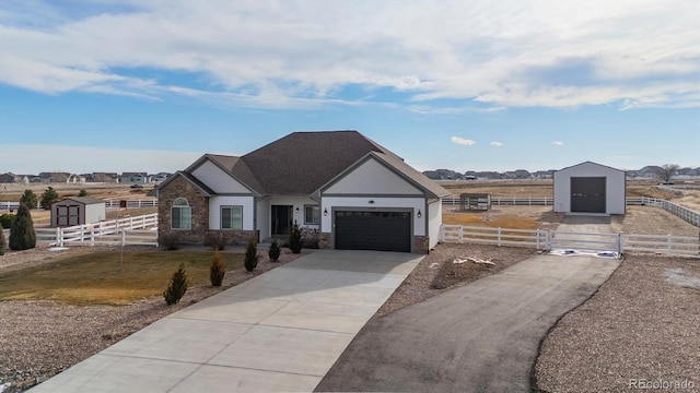 view of front of home featuring driveway, stone siding, a fenced front yard, and a garage