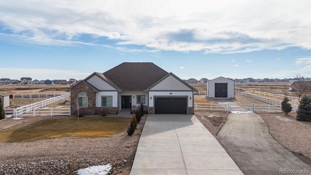 view of front of property with driveway, stone siding, a fenced front yard, and a garage