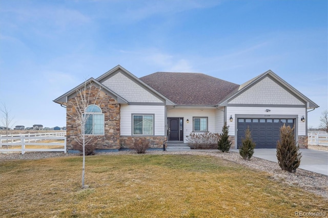 craftsman-style home with concrete driveway, a front yard, fence, a garage, and stone siding