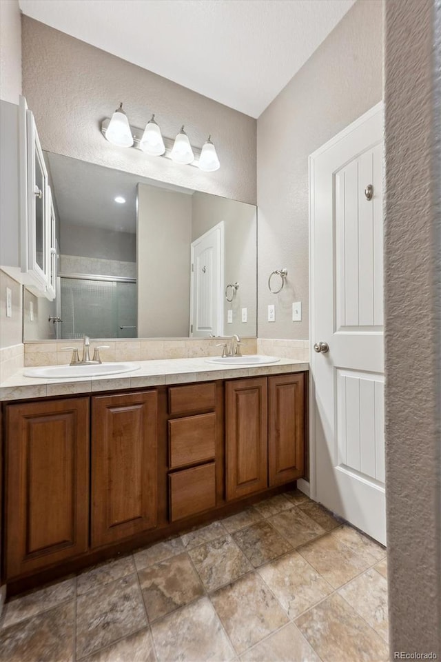 full bath with double vanity, a shower stall, and a sink