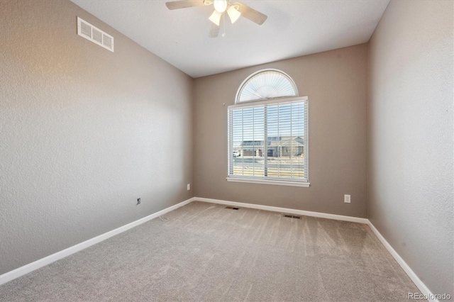 unfurnished room featuring baseboards, visible vents, ceiling fan, and carpet flooring