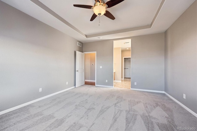 unfurnished bedroom featuring a raised ceiling, visible vents, and baseboards