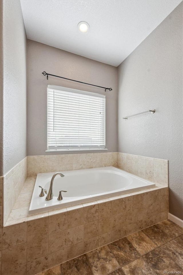 full bathroom featuring a garden tub, a textured ceiling, and a textured wall