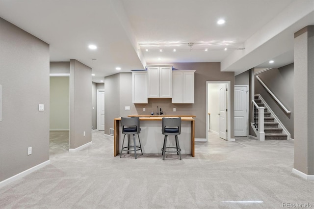 kitchen with light carpet, butcher block counters, a breakfast bar area, and white cabinets