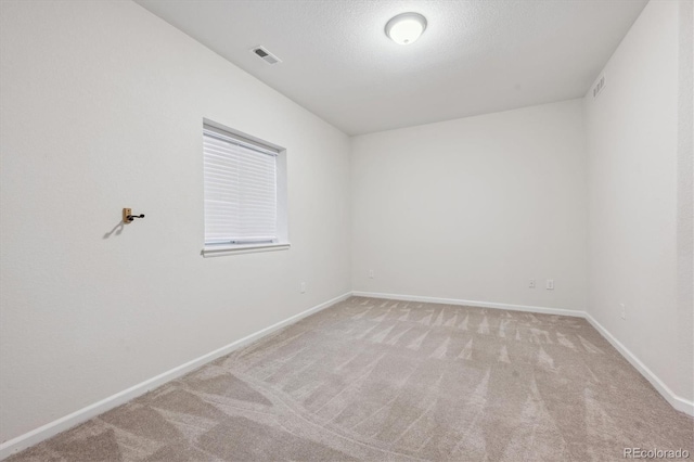 empty room with baseboards, a textured ceiling, visible vents, and carpet flooring