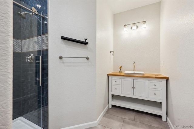 full bath featuring tile patterned flooring, a shower stall, vanity, and baseboards