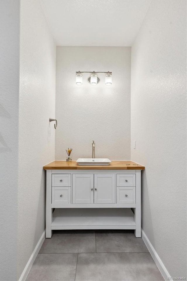 bathroom featuring a textured wall, vanity, and baseboards