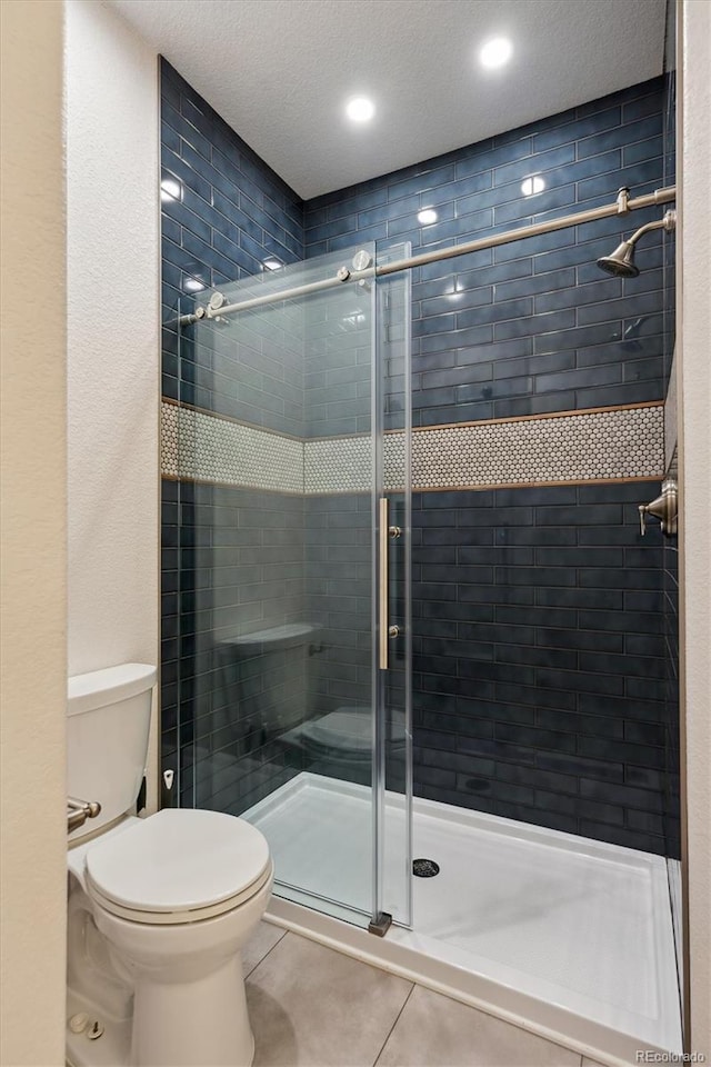 full bath featuring a stall shower, tile patterned flooring, and toilet