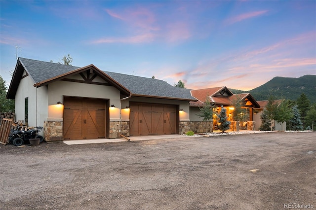 view of front of home with stone siding, stucco siding, an attached garage, and driveway