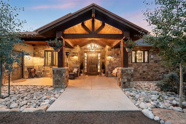 view of exterior entry with stone siding and a porch