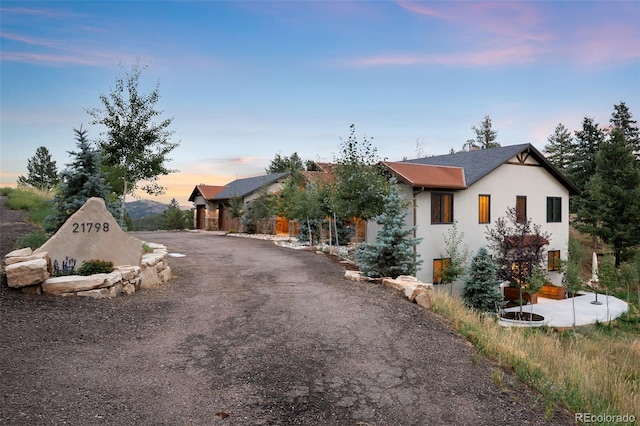 view of front of home with stucco siding and dirt driveway