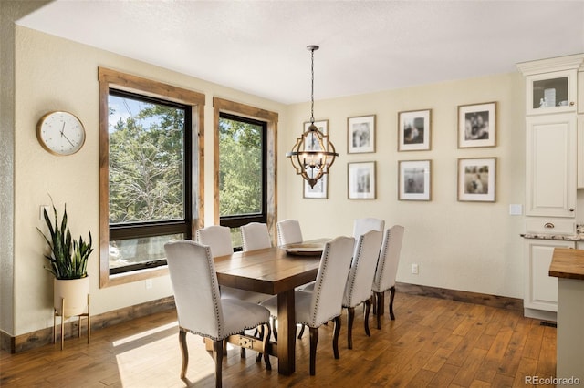 dining area with a notable chandelier, baseboards, and hardwood / wood-style floors