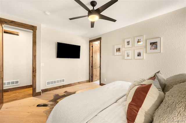 bedroom with wood finished floors, visible vents, and baseboards