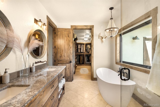 full bathroom featuring tile patterned flooring, double vanity, a notable chandelier, a soaking tub, and a sink