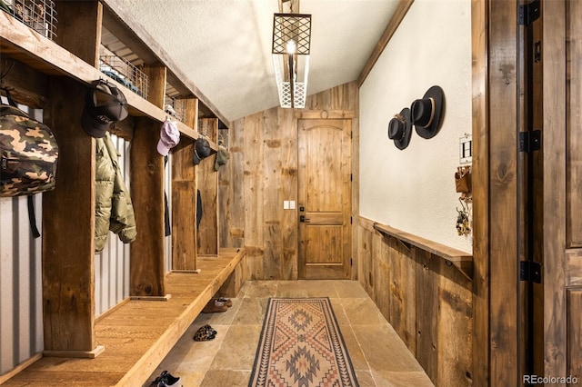 mudroom featuring a wainscoted wall, wood walls, and stone finish flooring