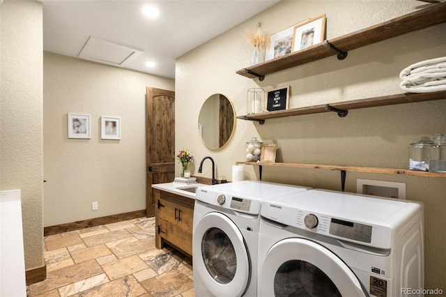 washroom with stone tile floors, baseboards, washing machine and clothes dryer, attic access, and a sink